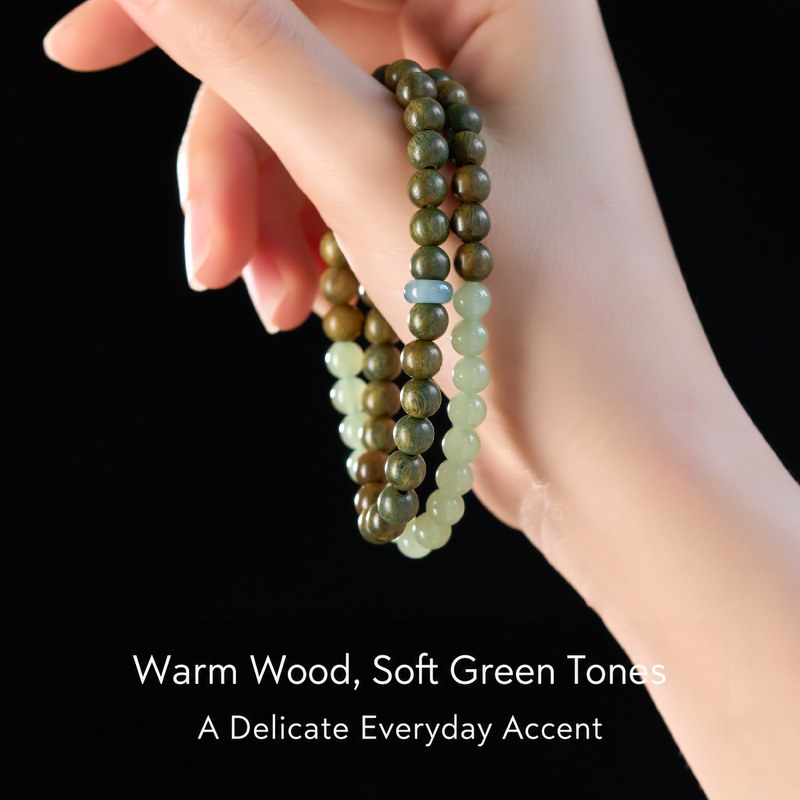 Double-wrap green sandalwood and jade bracelet held in hand