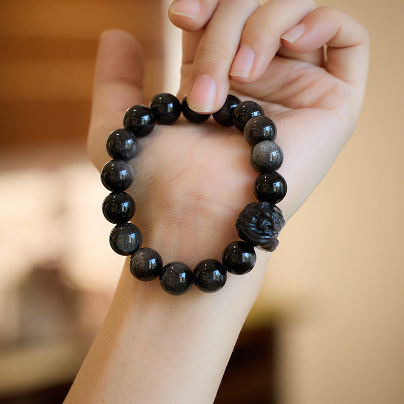 Silver-sheen obsidian bracelet showing polished beads and carved lion-dance head