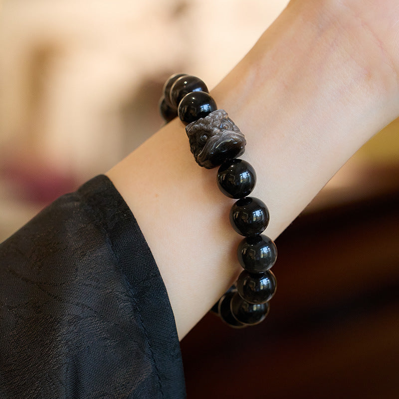 Silver-sheen obsidian bracelet showing polished beads and carved lion-dance head