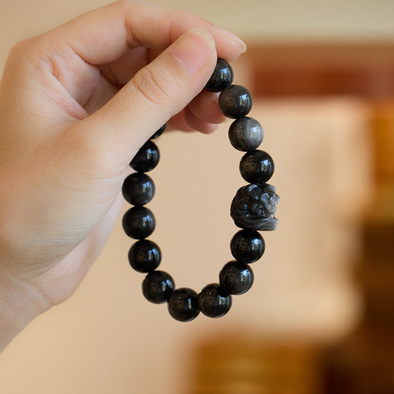 Silver-sheen obsidian bracelet showing polished beads and carved lion-dance head