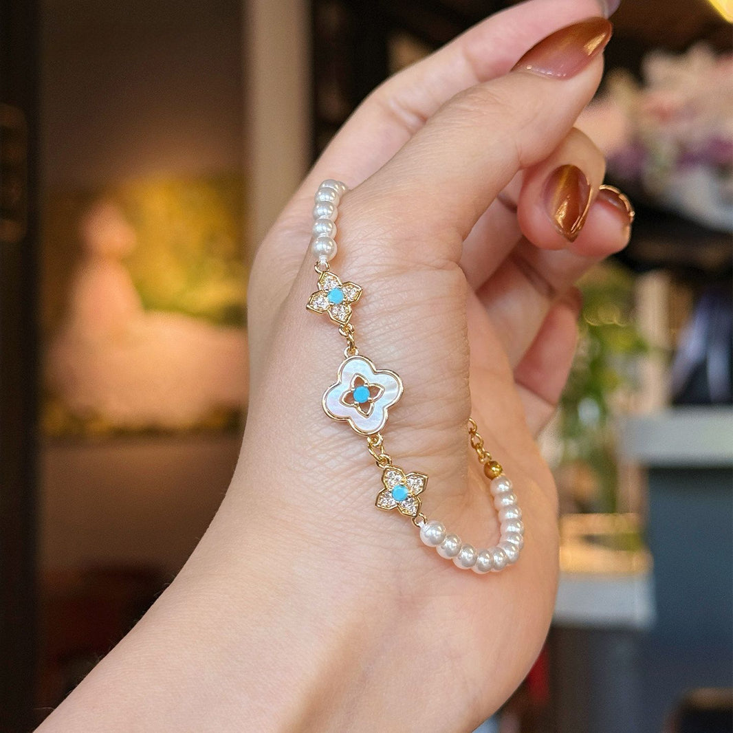 White bead bracelet with mother-of-pearl clover and gold-tone flower accents