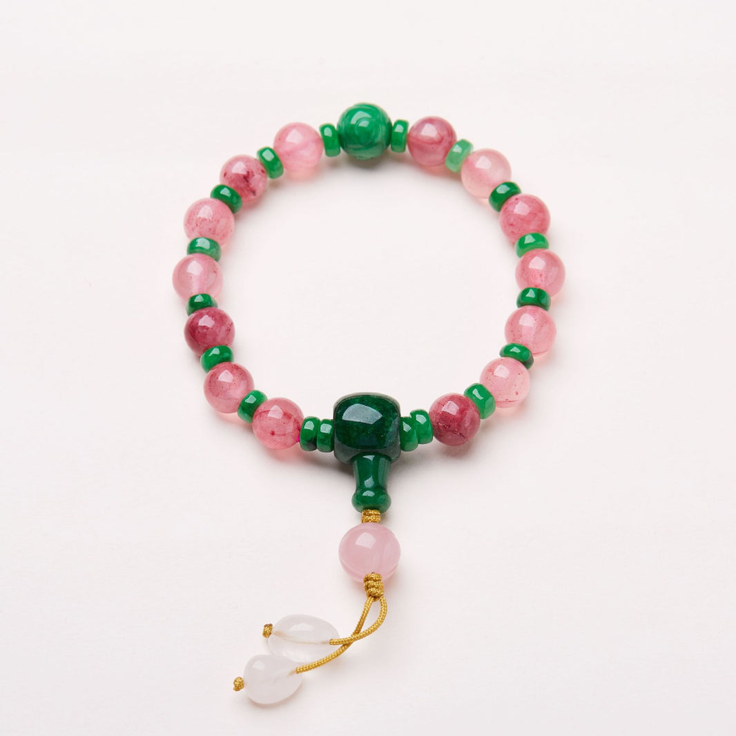 Pink patterned bead bracelet with green accents and knotted cord drops