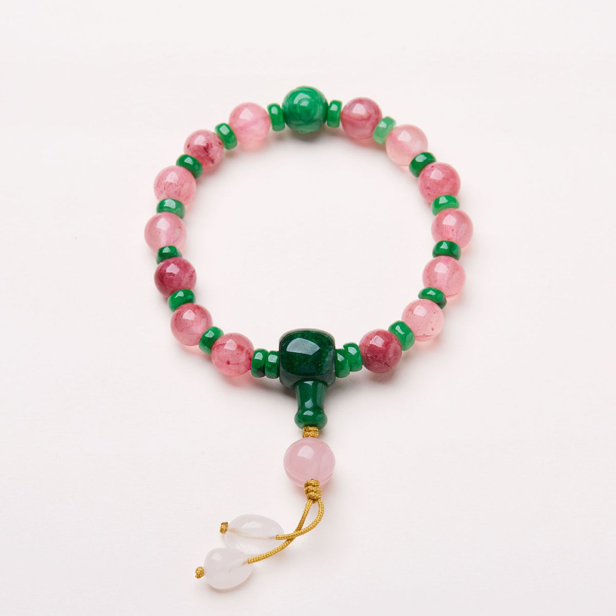 Pink patterned bead bracelet with green accents and knotted cord drops