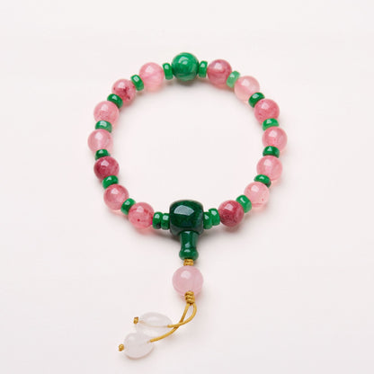 Pink patterned bead bracelet with green accents and knotted cord drops