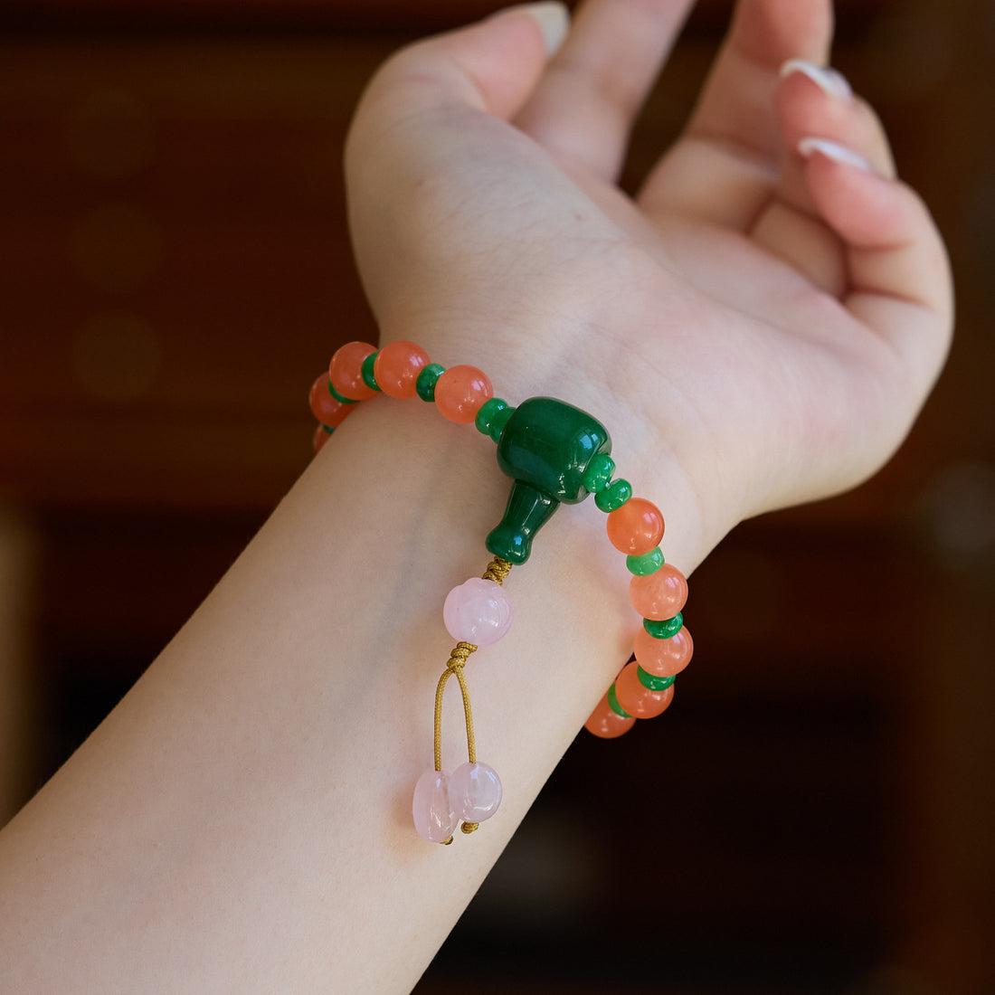 Orange bead bracelet with green accents worn on a wrist