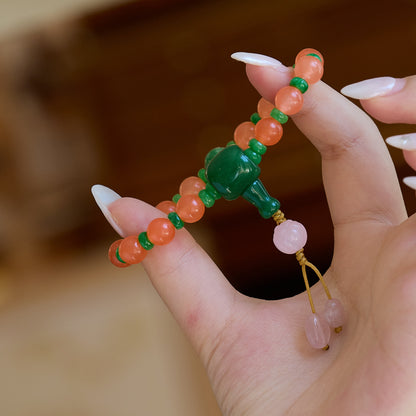 Orange bead bracelet with green accents held in a hand